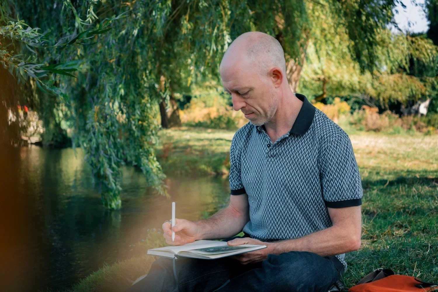 John Monks writing beside the river in Cambridge